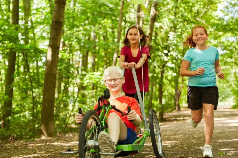 children-pushing-special-needs-tricycle