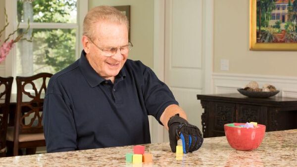 Elder using the SaeboGlove for Stroke Patients to move small objects