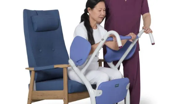 Elder woman using the Sara Stedy Patient Transfer Aid by ArjoHuntleigh to sit down on the couch