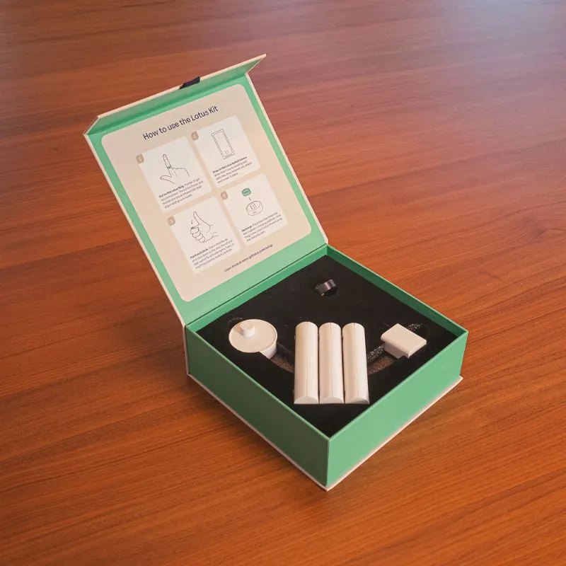 The Lotus Smart Ring with corresponding switch covers in it's packaging on a wooden table.