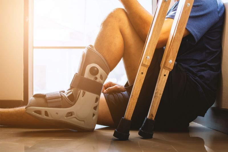 man-sitting-with-medical-boot-and-crutches