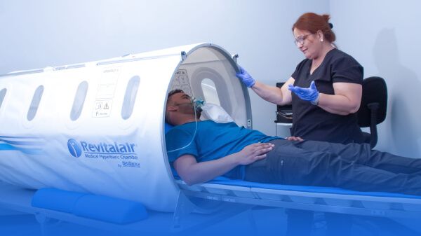 Man getting inside an hyperbaric chamber with the help of a healthcare professional