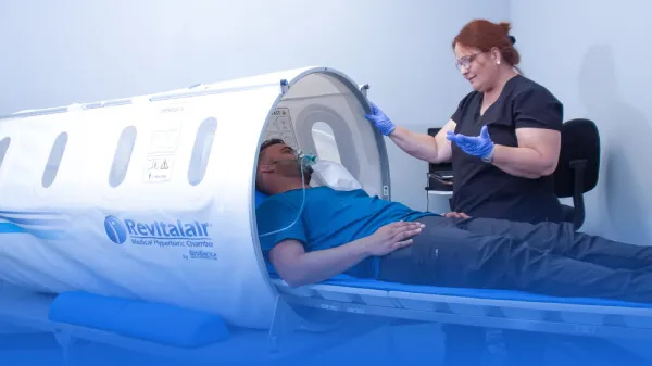 Man getting inside an hyperbaric chamber with the help of a healthcare professional