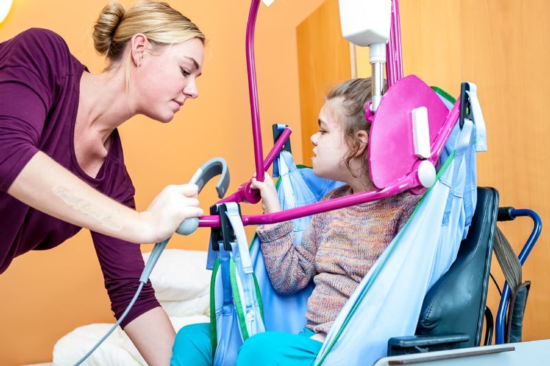 nurse-lifts-child-in-wheelchair-with-sling