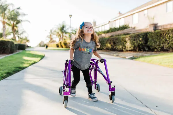Toddler girl using the Drive Nimbo Posterior Pediatric Walker and Gait Trainer to walk