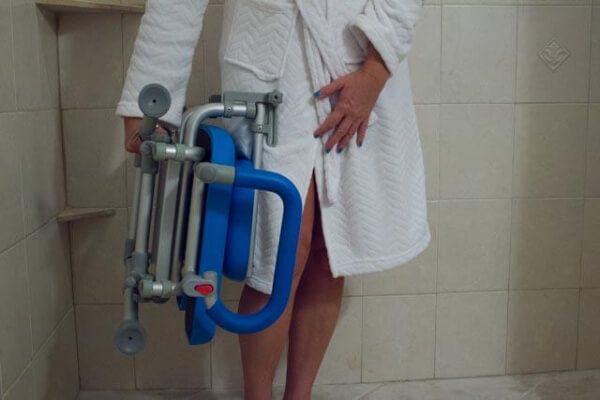 Woman holding the UltraCommode Shower Commode Chair by Platinum Health with one hand