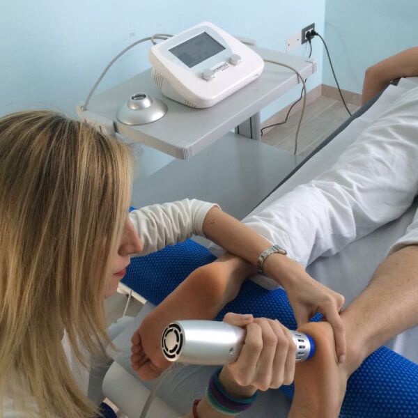 Woman medical professional treating patient with shockwave therapy on his foot