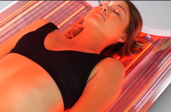 Woman under red light therapy chamber