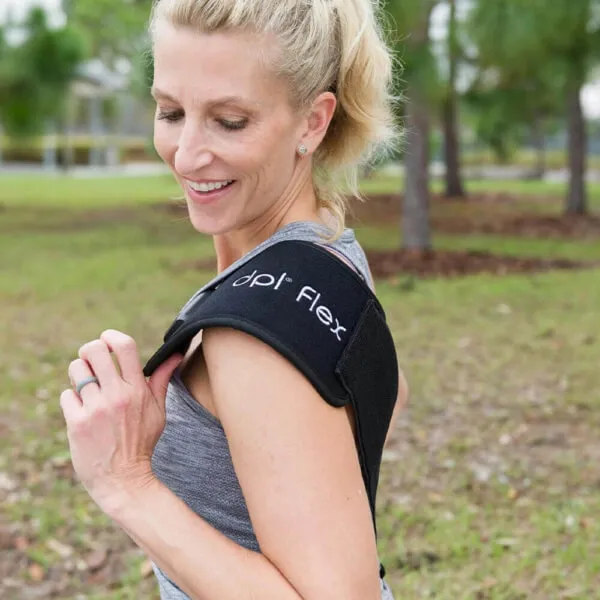 Woman using a portable red light therapy device to recover her shoulder