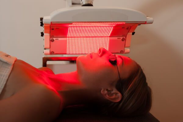 Woman using red light therapy to treat facial acne